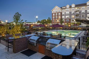 a grill area and pool at night at Reveal Hackensack apartments